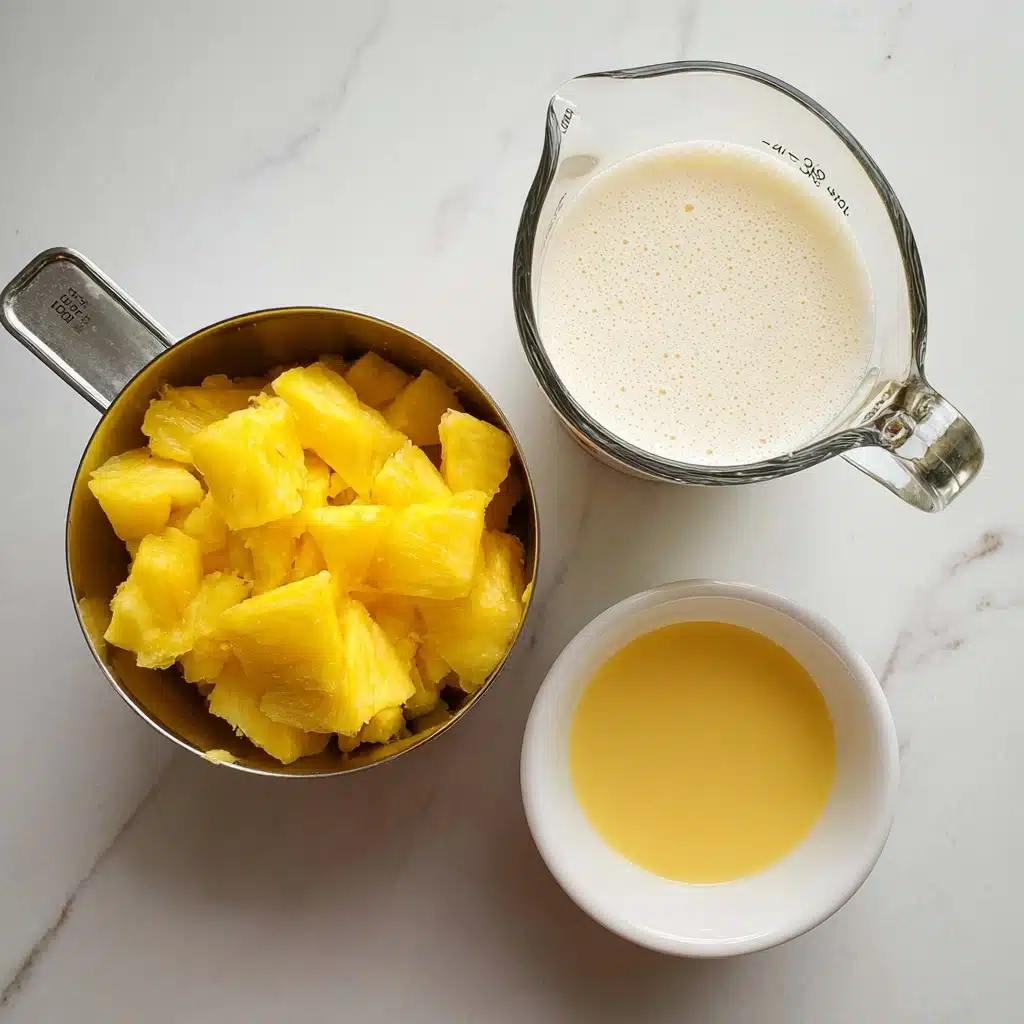 The image shows a single-layer dessert with a creamy, velvety texture, swirled smoothly within a round transparent bowl. The layer is a soft pastel yellow, very uniform in color and texture, reminiscent of freshly churned ice cream or gelato. The surface has gentle swirls and ridges, indicating it has been recently scooped or stirred, with slightly uneven edges where the creamy layer meets the sides of the bowl. The bowl sits on a light-colored marble counter with subtle grey veining, providing a clean and fresh backdrop. photo taken with an iphone