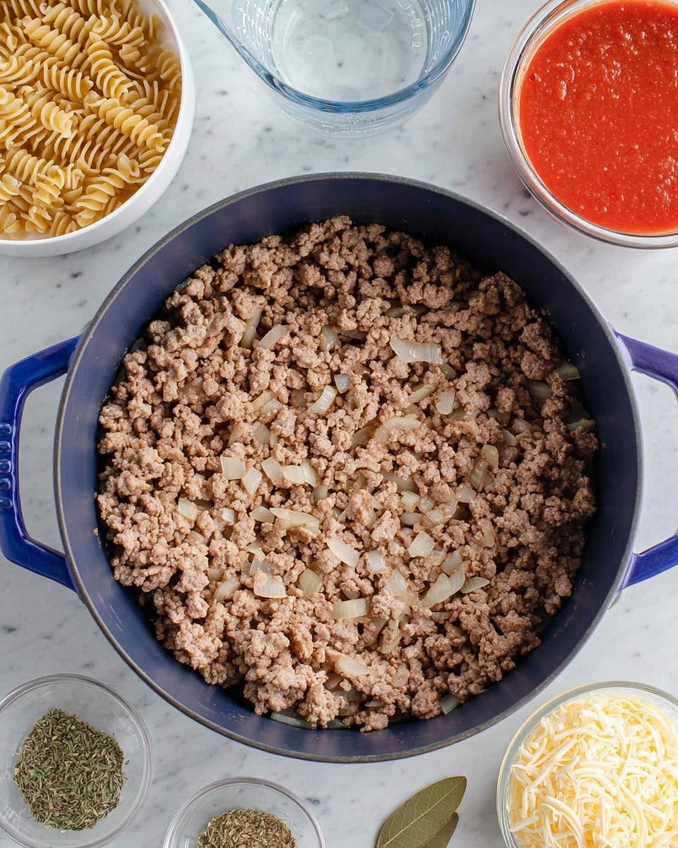 A top view of a dark blue pot filled with a single layer of cooked ground meat mixed with small pieces of translucent cooked onion, resting on a white marbled surface. Around the pot, starting from the top left corner, there is a white bowl with two layers of light brown curly-edged pasta, a clear glass measuring cup with water, a white bowl filled with bright red tomato sauce, a white bowl of mixed green and red dried herbs and spices with two bay leaves on top, and a white bowl with one layer of shredded pale yellow cheese. photo taken with an iphone --ar 4:5 --v 7