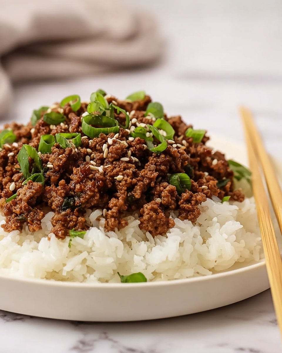 A white plate holds a base layer of white steamed rice with soft, separate grains. On top is a thick layer of cooked minced meat, showing a rich brown color with a slightly crumbly texture. The meat is sprinkled with small white sesame seeds and bright green chopped scallions, adding pops of color. Two light wooden chopsticks lean on the edge of the plate. The background shows a soft focus with neutral tones, and the whole scene is set on a white marbled surface. Photo taken with an iphone --ar 4:5 --v 7