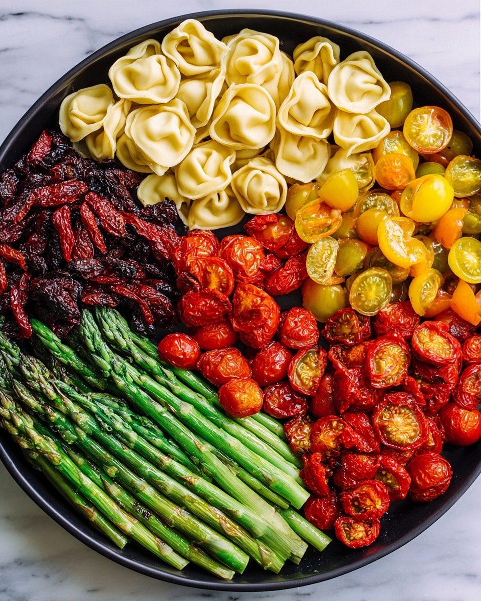 A round black tray is arranged with five different sections of food. Starting from the top left and moving clockwise, there is a layer of pale yellow tortellini with a smooth texture, followed by a dark red, wrinkled pile of sun-dried tomatoes. Next is a cluster of bright yellow cherry tomatoes cut in half, showing their juicy interior, then a group of red cherry tomatoes also halved, revealing a juicy inside. At the bottom left, a bunch of fresh green asparagus spears is placed side by side with a smooth, slightly shiny texture. The tray sits on a white marbled surface. photo taken with an iphone --ar 4:5 --v 7