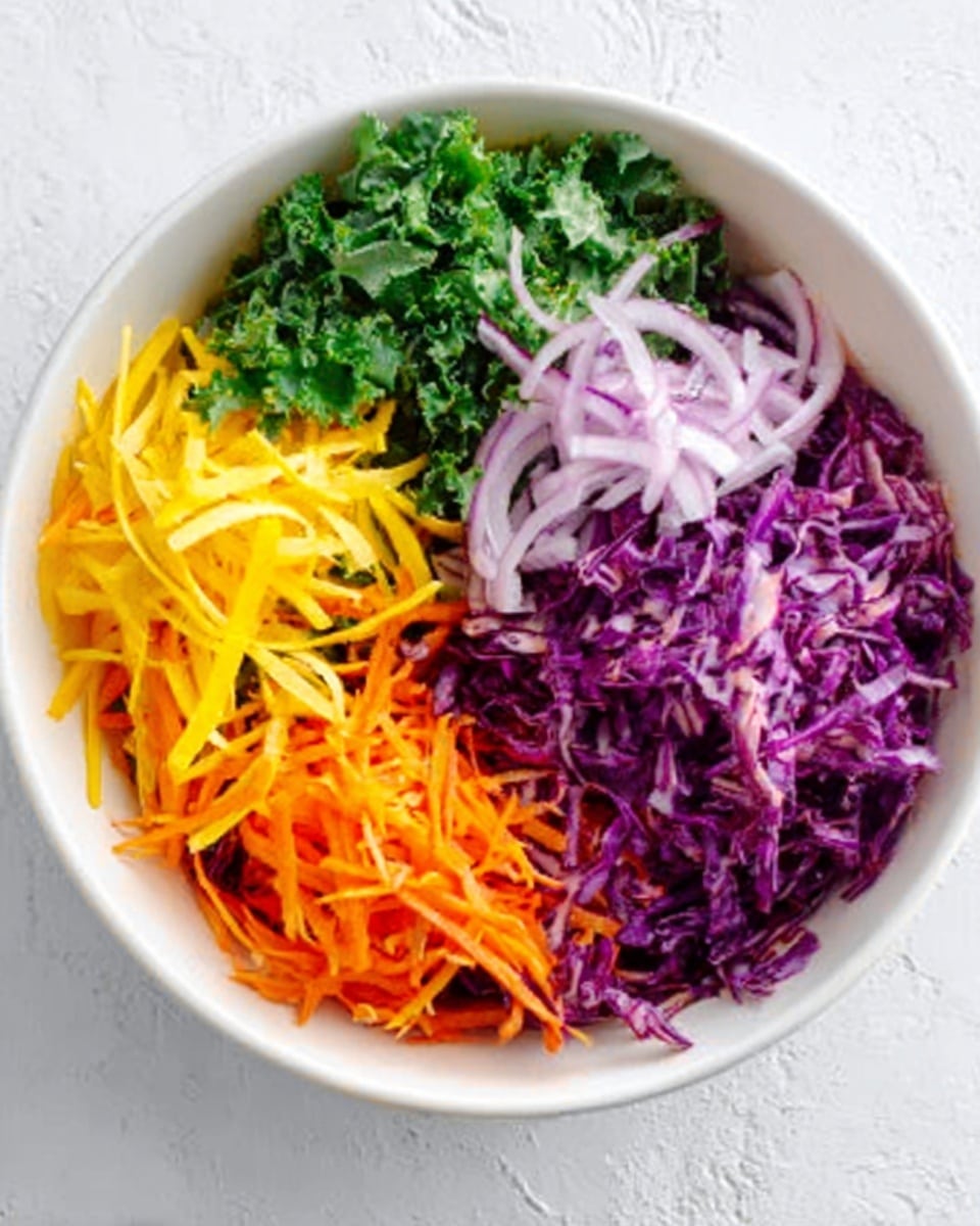 A white bowl filled with four colorful layers of finely shredded vegetables, placed on a white marbled surface. The bottom right layer is purple cabbage mixed with thin orange carrot strips, showing a mix of deep purple and bright orange colors. Above it, slightly to the left, is a pile of green kale leaves with a rough, leafy texture. To the top left is a layer of thin, long yellow strips, likely bell pepper or cheese, bright and shiny. To the top right are thin rings of light purple onion, soft and slightly translucent. The layers are separated but fill the bowl evenly and vibrantly. Photo taken with an iphone --ar 4:5 --v 7
