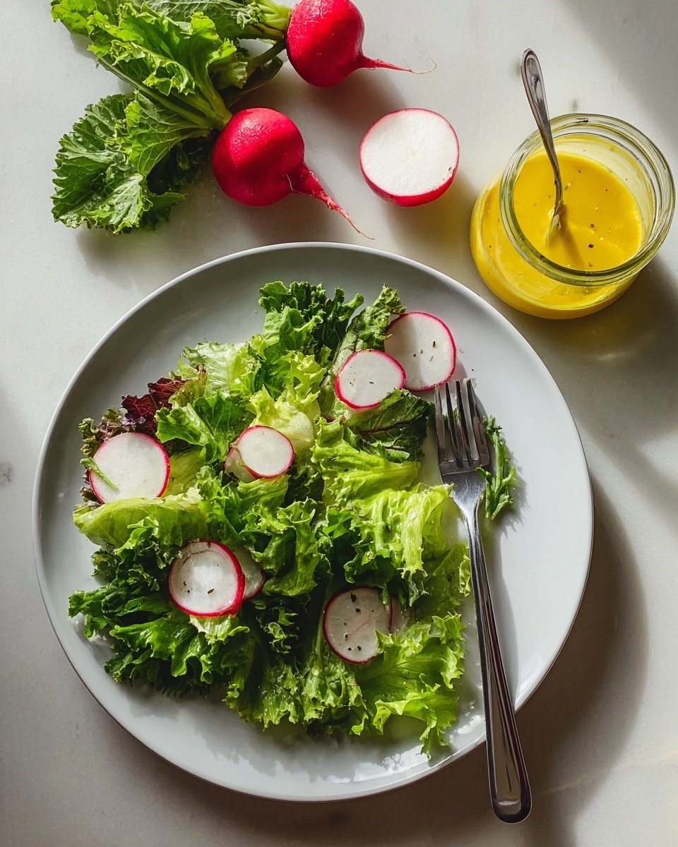 A white plate sits on a white marbled surface with fresh salad made of layered leafy greens in different shades of bright and dark green, topped with thin round slices of red radish with white centers scattered on top. To the left of the plate is a silver fork resting on the plate’s edge. Above the plate, there are two whole radishes, one cut in half showing a white inside, and a small jar filled with bright yellow dressing with a spoon inside it. The lighting highlights the fresh textures of the salad and the smooth surface of the dressing jar. Photo taken with an iphone --ar 4:5 --v 7