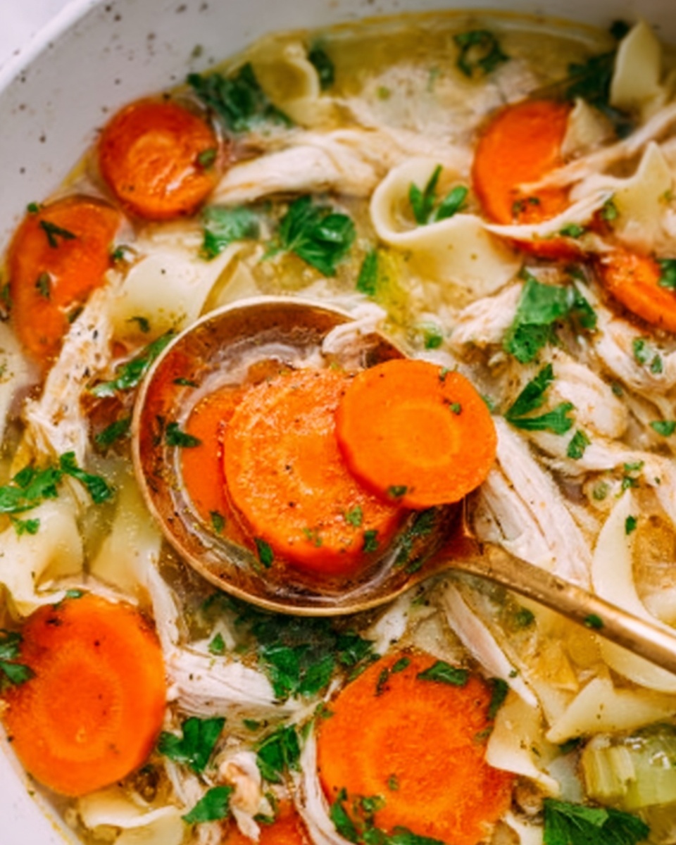 Easy Rotisserie Chicken Noodle Soup Recipe 6 The image shows a close-up of a white bowl filled with chicken soup. The soup has visible layers including shredded white chicken meat, round bright orange carrot slices, wide flat pale yellow noodle strips, and light green parsley leaves scattered on top. A golden spoon held by a woman's hand is dipping into the soup, lifting a round carrot slice and some noodles. The white marbled surface underneath complements the warm colors of the soup. photo taken with an iphone --ar 4:5 --v 7