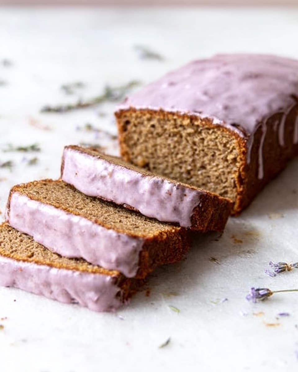 A loaf of brown bread with a smooth pale purple glaze spread evenly on top, placed on a clean white surface with a white marbled texture. Four thick slices are partially cut from the loaf on the left side, showing a dense, moist interior with a fine crumb texture. There are small lavender flowers scattered lightly on the surface around the bread, adding a delicate detail. The lighting is soft and natural, emphasizing the subtle colors and textures of the bread and glaze. photo taken with an iphone --ar 4:5 --v 7