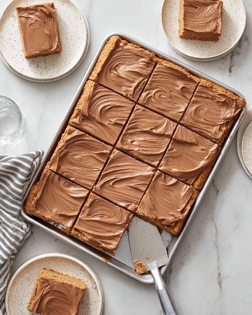 The image shows a large rectangular tray filled with a dessert cut into twelve square pieces. The dessert has two layers: a bottom layer with a rough, golden-brown cookie or crust texture, and a smooth, thick layer of light brown chocolate frosting spread evenly on top with swirled patterns. Three pieces are removed from the tray with a metal spatula on the right side, showing the clean layers. Two of these pieces are placed next to the tray on the white marbled surface, and one piece is on a white plate with a speckled pattern in the upper left corner. A clear glass and two more white speckled plates are in the background with a striped cloth near the bottom left corner. Photo taken with an iphone --ar 4:5 --v 7