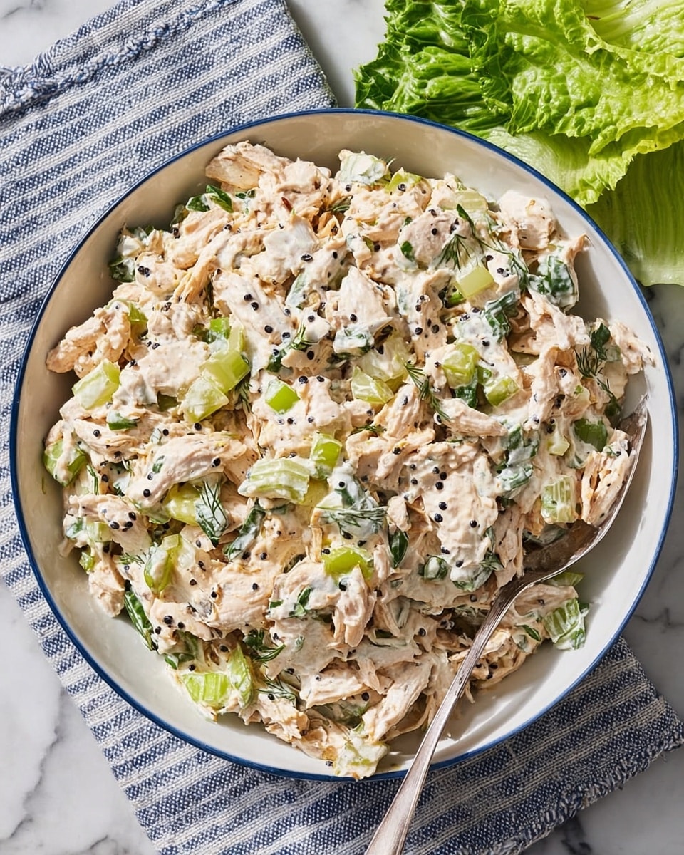 The image shows a close-up of a white bowl filled with shredded light beige chicken mixed with bright green celery slices, small pieces of red onion, and bits of green herbs, all tossed together in a fresh salad. A silver fork lifts a portion of the salad above the bowl, showing the mix of soft, stringy chicken and crunchy vegetables. The background is a white marbled texture with a blurred yellow drink visible in the back. The lighting highlights the textures and colors of the ingredients clearly. photo taken with an iphone --ar 4:5 --v 7