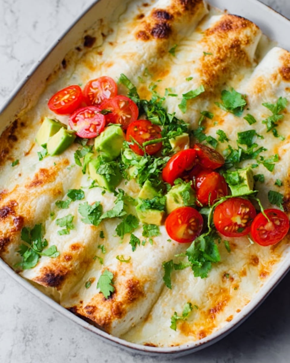 The image shows a white plate with three rolled enchiladas placed side by side. The enchiladas are covered in melted cheese that looks creamy and golden on top with some brown spots. On the middle enchilada, there are multiple colorful layers of fresh toppings: bright red cherry tomatoes cut in halves, green avocado chunks, and fresh green cilantro leaves scattered on top. The white marbled surface underneath adds a clean and fresh look to the scene. photo taken with an iphone --ar 4:5 --v 7