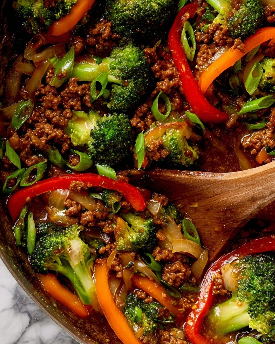 A close-up view of a colorful stir-fry dish in a pan, showing three main layers: vibrant green broccoli florets with a rough texture sitting on and mixed through irregular small brown cooked ground meat pieces, bright red and orange bell pepper slices curved and glossy scattered throughout, and translucent cooked onion strips with a soft, shiny look. There are also sliced light green scallions sprinkled on top, adding a fresh contrast. A wooden spoon with a smooth, polished surface is partially immersed in the sauce that coats the ingredients, giving a rich, shiny appearance. The background shows a white marbled texture. Photo taken with an iphone --ar 4:5 --v 7