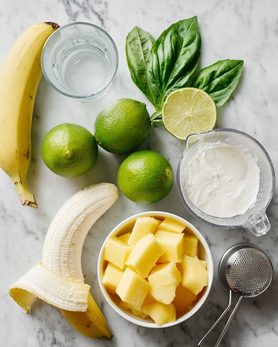 The image shows fresh ingredients on a white marbled surface. There is one peeled banana lying near the bottom left, with one unpeeled yellow banana partially visible. Three green limes are placed near the center, one cut in half showing its light green inside. Bright green basil leaves are arranged near the top left, showing their smooth texture and veins. A clear glass with white liquid is near the banana. A white bowl filled with yellow frozen mango cubes is on the bottom right. A metal citrus squeezer is visible next to the limes, with a half cup of white creamy yogurt and a metal measuring cup also placed near the bottom. The photo taken with an iphone --ar 4:5 --v 7