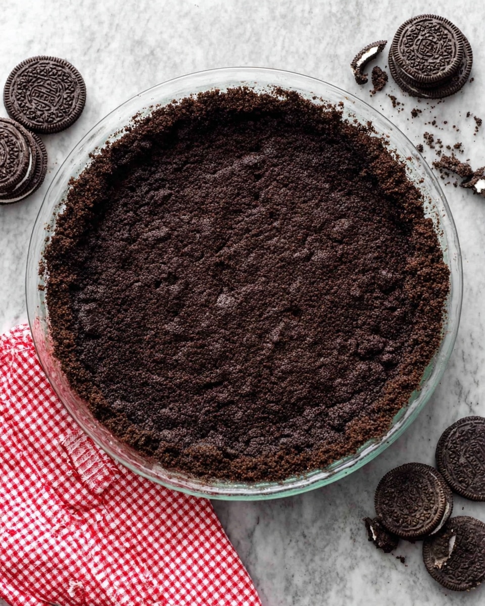 The image shows a close-up of a slice of cookies and cream pie being lifted on a silver pie server. The pie has three layers: the bottom dark brown and crumbly chocolate cookie crust, the middle light cream layer mixed with crushed dark chocolate cookies creating a speckled texture, and the top layer of smooth white whipped cream with two swirled dollops. The pie slice reveals a dense and creamy texture with dark cookie bits evenly spread inside. In the background, the remaining pie sits on a white marbled surface. Photo taken with an iphone --ar 4:5 --v 7