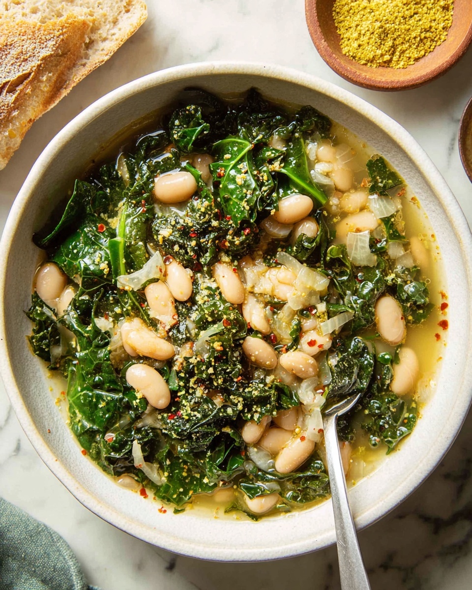 A white bowl filled with a soup made of white beans and dark green leafy kale leaves mixed with small white onion pieces in a clear broth. The soup has a light sprinkling of yellow powder and tiny red pepper flakes on top. A spoon rests inside the bowl on the right side. In the background, there is a white marbled surface with a small brown bowl of yellow powder and a piece of light brown bread at the top left corner. Photo taken with an iphone --ar 4:5 --v 7
