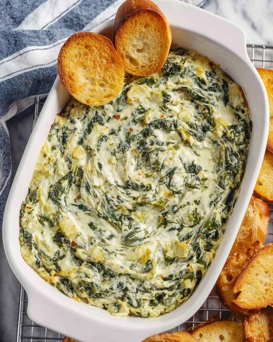 A white rectangular dish filled with creamy spinach and artichoke dip, showing a smooth, swirled texture with a mix of vibrant green spinach leaves and pale yellow and white creamy sauce evenly spread across the entire surface. Two toasted round bread slices with a golden brown color rest partially inside the dip on the top left corner. The dish sits on a white marbled surface with a blue and white striped towel on the upper left side, and a cooling rack beneath with more toasted bread slices scattered on the right side. Photo taken with an iphone --ar 4:5 --v 7