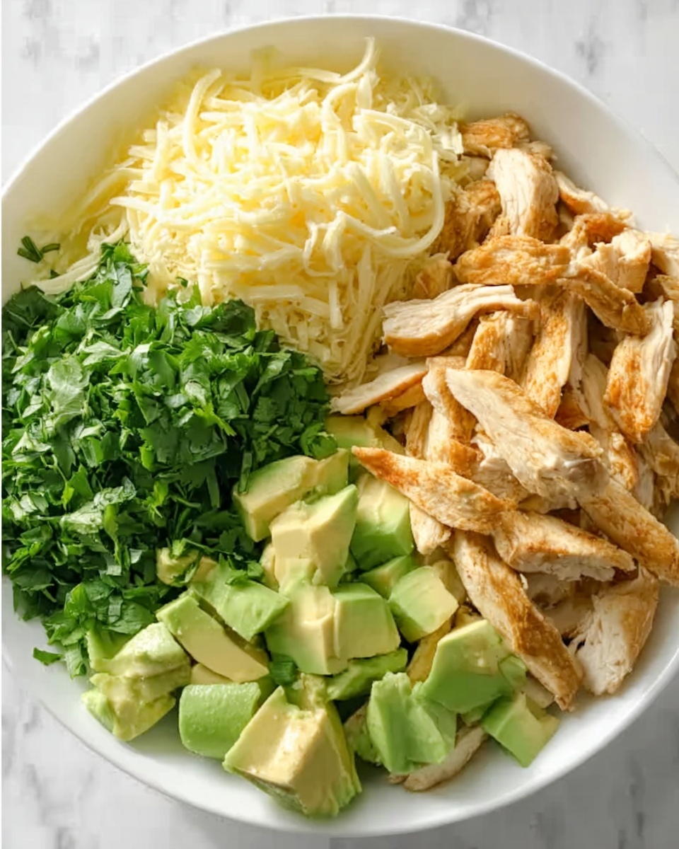 A white bowl is filled with four sections of ingredients arranged in neat piles. The first section has shredded pale yellow cheese with a soft texture. Next to it, there is a bunch of bright green chopped cilantro with a leafy texture. The third section contains medium-sized chunks of light green avocado with a smooth surface. The last section has many strips of cooked chicken that are golden-brown with a slightly crisp outside. The bowl is placed on a white marbled surface. photo taken with an iphone --ar 4:5 --v 7