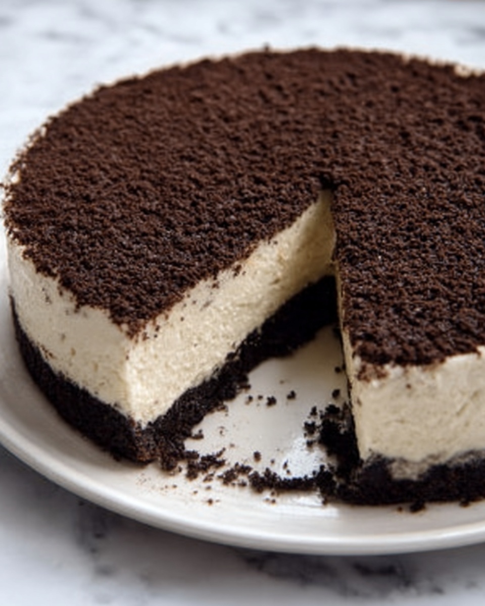 A round dessert cake with three visible layers sits on a white plate over a white marbled surface. The bottom layer is dark brown and crumbly, acting like a firm crust. Above it is a thick, creamy white layer that looks smooth and soft. The top layer is a dark, fine, crumb-like topping evenly spread across the cake. A slice is removed, showing the clean division between the three layers clearly. Photo taken with an iphone --ar 4:5 --v 7