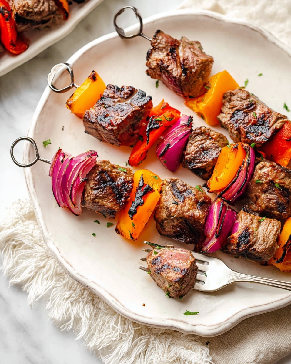 Two skewers lie on a white ceramic plate with a scalloped edge. Each skewer has four pieces of grilled brown meat with char marks, alternating with grilled vegetables: bright orange and red bell pepper chunks and purple onion pieces with slightly blackened edges. One skewer is partly pierced by a silver fork holding a cube of meat showing a pink center. In the corner of the image, part of a white dish with more skewers is visible on a white marbled surface. A fringed white cloth is partially under the plate. photo taken with an iphone --ar 4:5 --v 7