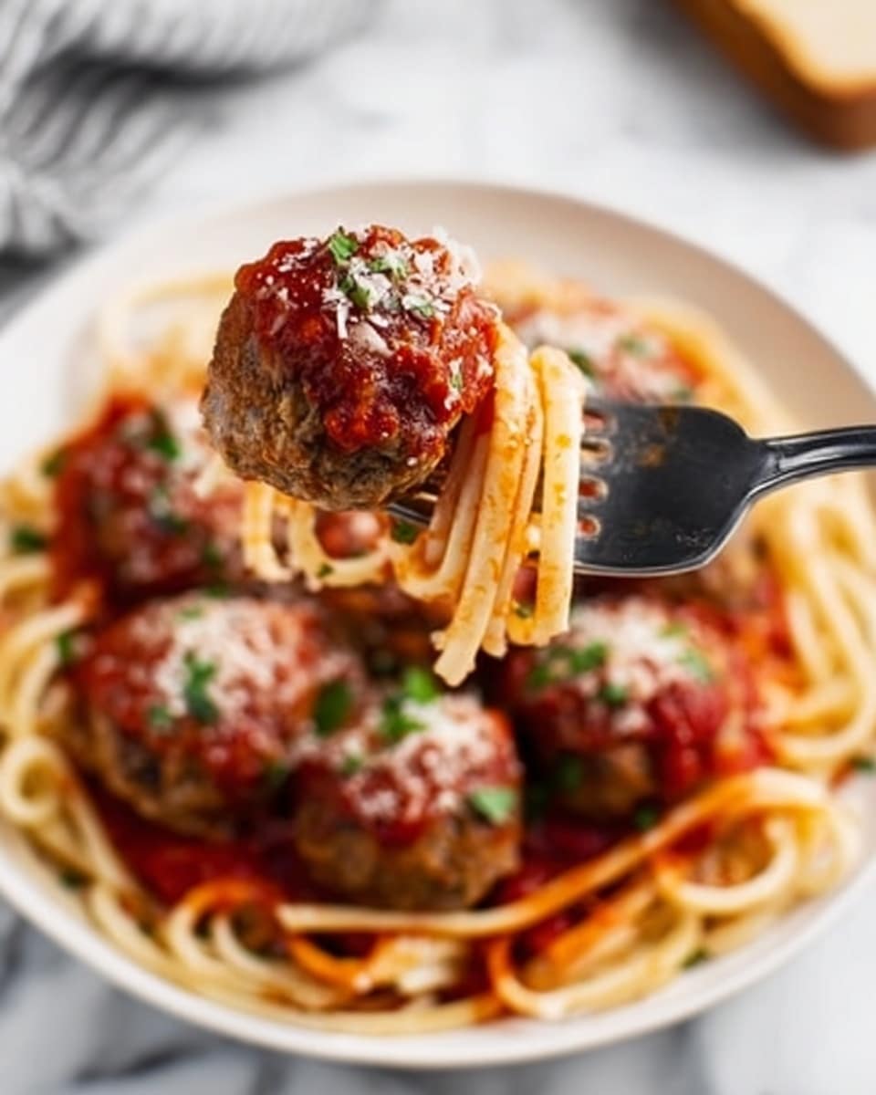 A close-up image showing a fork holding a round meatball topped with red sauce and a sprinkle of cheese and green herbs. In the background, a white plate holds a bed of spaghetti covered with red marinara sauce, with several more meatballs placed on top, each similarly garnished with cheese and herbs. The plate rests on a white marbled surface, and the whole scene is brightly lit, emphasizing the textures and colors of the food. Photo taken with an iphone --ar 4:5 --v 7