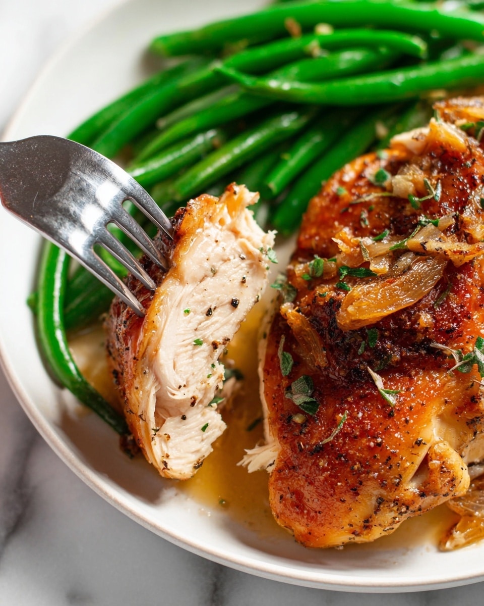 The image shows a close-up of a white plate with three main layers: a base layer of bright green green beans on the top side, a top layer of golden-brown roasted chicken with crispy skin sprinkled with small bits of garlic and chopped green herbs, and a middle layer where a silver fork pierces a tender, light-colored piece of the chicken meat, lifting it slightly. The chicken is juicy, with visible seasoning and small black specks of pepper. The plate rests on a white marbled surface, and the scene is lit brightly, showing the textures clearly. Photo taken with an iphone --ar 4:5 --v 7