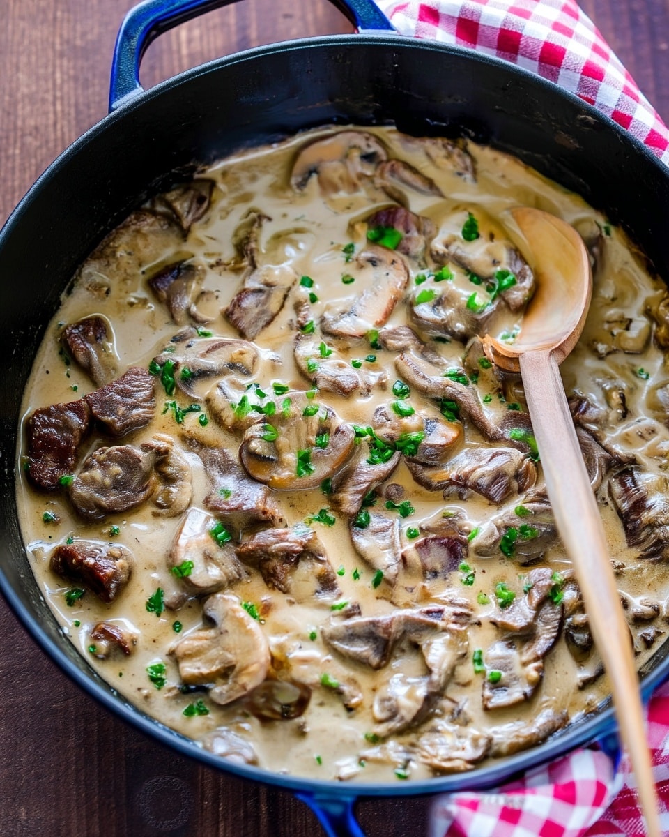 A close-up view of a creamy mushroom and meat stew with a thick, light brown sauce. The dish shows several slices of mushrooms with a light beige color and a tender texture, mixed with strips of cooked brown meat. Bright green chopped herbs are sprinkled evenly on top, adding a fresh color contrast. A wooden spoon is resting in the dish on the right side, partially covered by the sauce. The background has a white marbled texture. photo taken with an iphone --ar 4:5 --v 7