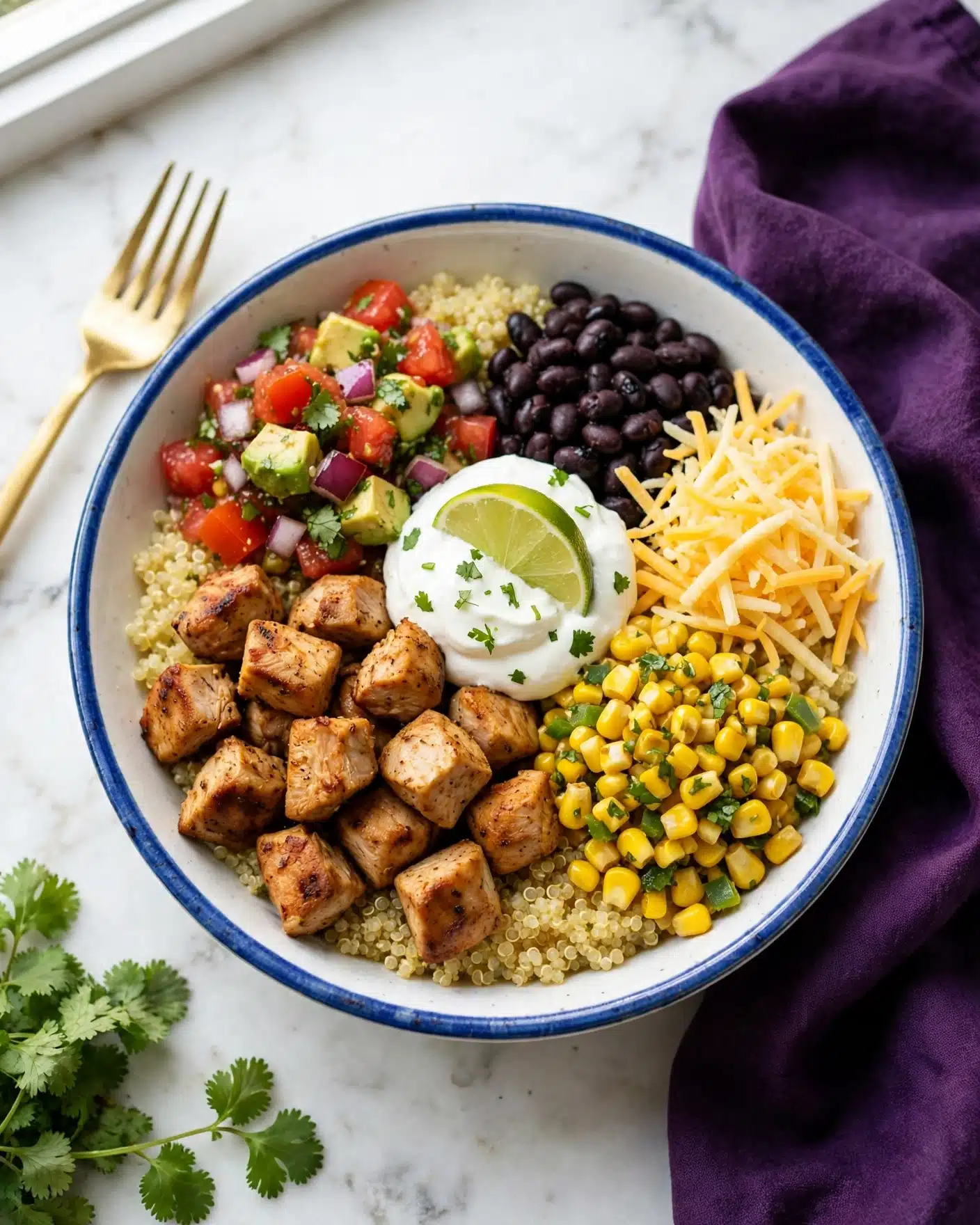 A white bowl with a blue rim shows a colorful layered dish. The bottom layer is fluffy light yellow quinoa covering the bowl. On top, five sections form a circle: brown grilled chicken cubes on the front left, bright red and green chunky salsa with avocado and red onion on the top left, a small pile of black beans on the top right, golden yellow corn with green bits on the bottom right, and some shredded yellow cheese next to the beans. In the center is a dollop of white sour cream topped with a green lime wedge and tiny green herb pieces. A gold fork rests on the left side of the bowl. The bowl is on a white marbled surface with a deep purple cloth to the right and fresh green cilantro in the bottom left corner. Photo taken with an iphone --ar 4:5 --v 7
